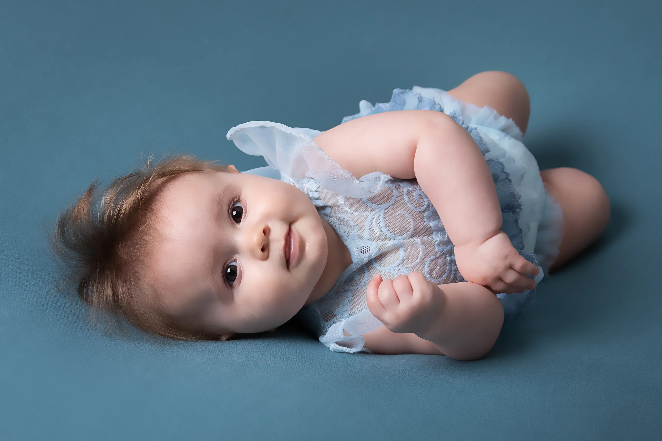 Bébé fille photographiée sur le dos sur un tissu de couleur unie au studio photo de Baugy proche de Nevers